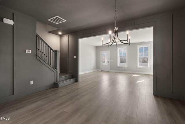 unfurnished dining area featuring hardwood / wood-style flooring and an inviting chandelier