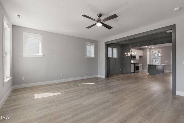 unfurnished living room featuring sink, hardwood / wood-style flooring, and ceiling fan with notable chandelier