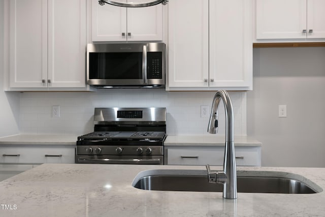 kitchen featuring light stone countertops, appliances with stainless steel finishes, sink, and white cabinets