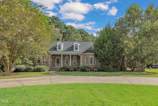 cape cod home featuring covered porch and a front lawn