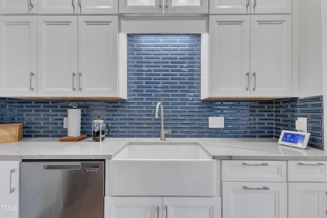 kitchen with light stone counters, sink, white cabinetry, and stainless steel dishwasher