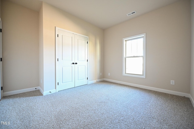 unfurnished bedroom with light carpet and a closet