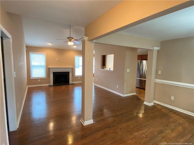 unfurnished living room featuring decorative columns, dark hardwood / wood-style flooring, and ceiling fan