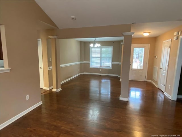 interior space with dark hardwood / wood-style flooring, lofted ceiling, a chandelier, and decorative columns