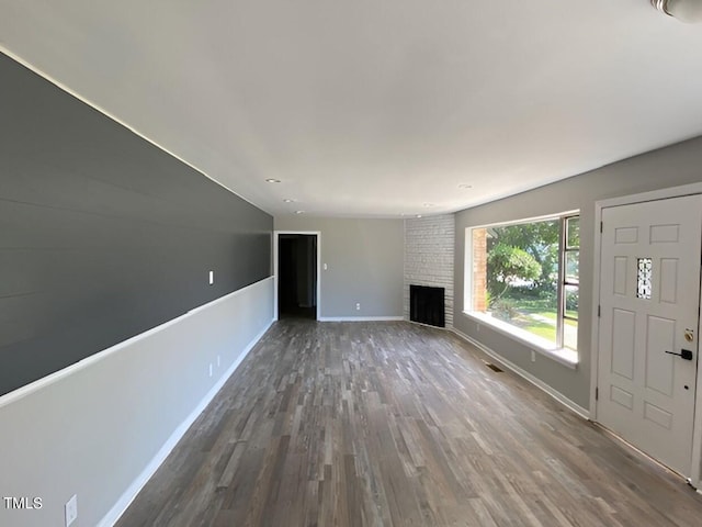 unfurnished living room with hardwood / wood-style floors, vaulted ceiling, and a brick fireplace