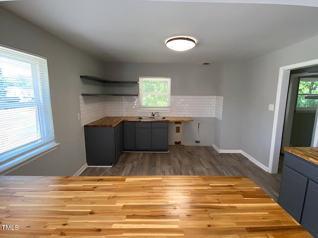 kitchen featuring sink, light hardwood / wood-style floors, tasteful backsplash, and wooden counters