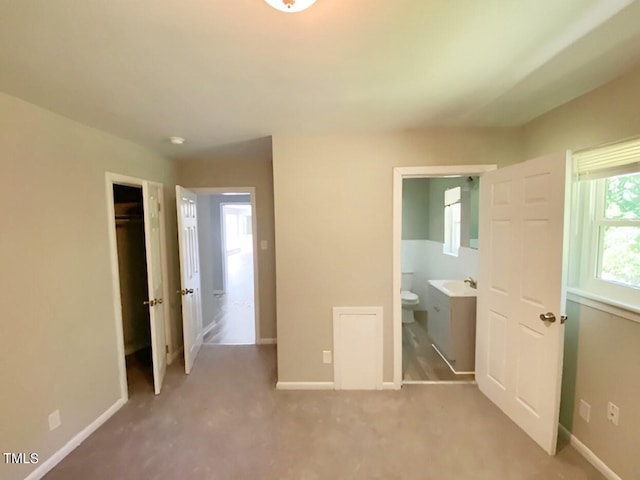 unfurnished bedroom featuring a closet, light carpet, and ensuite bathroom