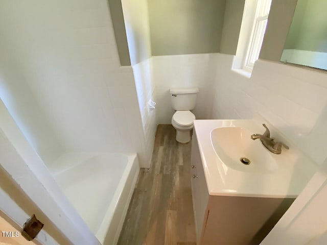 bathroom with vanity, toilet, a bath, and wood-type flooring