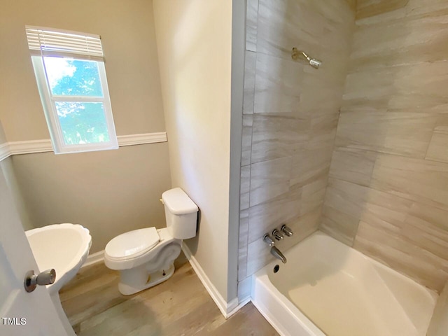 bathroom featuring wood-type flooring, toilet, and tiled shower / bath combo