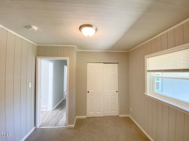 unfurnished bedroom with a closet, carpet flooring, and ornamental molding