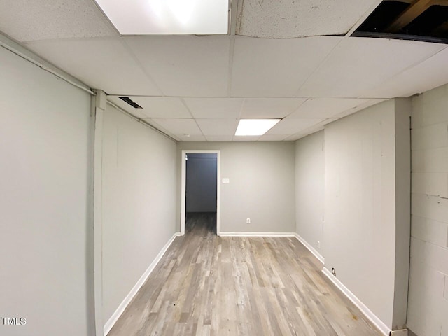 basement with a drop ceiling and light hardwood / wood-style flooring