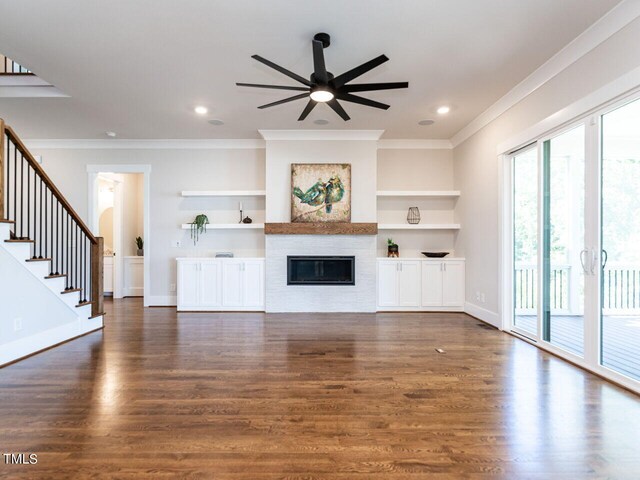 unfurnished living room with built in features, plenty of natural light, ceiling fan, and dark hardwood / wood-style flooring