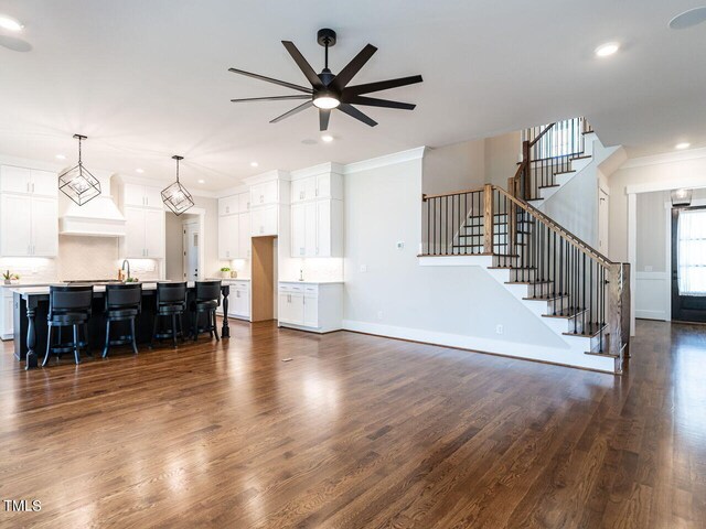 living room featuring crown molding, dark wood-type flooring, ceiling fan, and sink