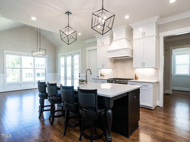 kitchen featuring a center island with sink, white cabinetry, and lofted ceiling