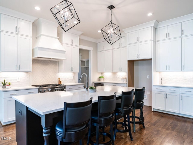 kitchen featuring white cabinetry, custom range hood, and a kitchen island with sink