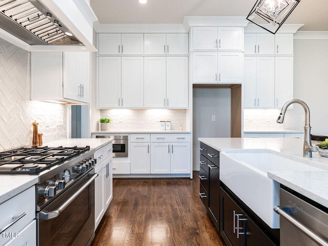 kitchen with premium range hood, ornamental molding, a sink, appliances with stainless steel finishes, and white cabinets