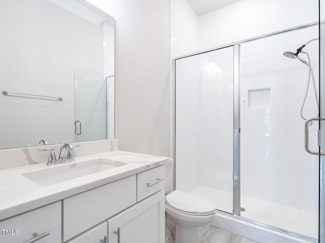 bathroom featuring toilet, a shower with door, and vanity