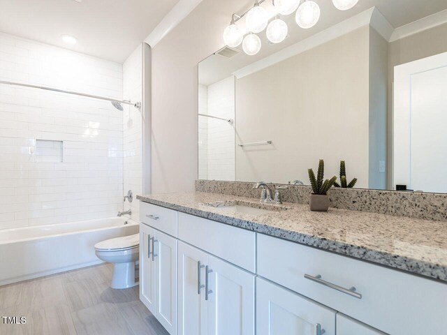 full bathroom with tiled shower / bath, vanity, and toilet