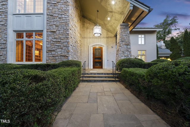 property entrance featuring stucco siding and stone siding