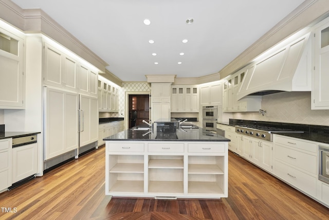 kitchen with a sink, appliances with stainless steel finishes, wood finished floors, and open shelves