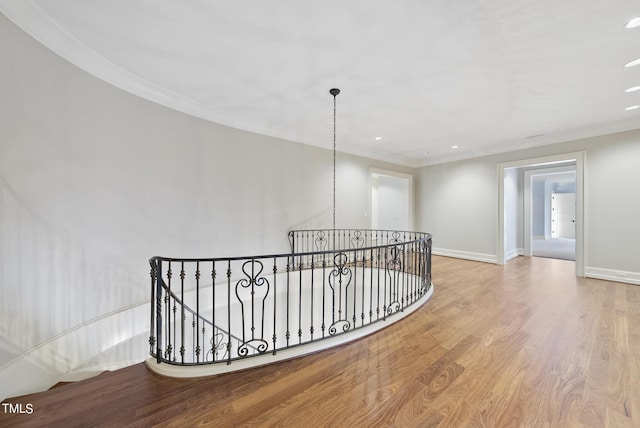 hall with wood finished floors, baseboards, recessed lighting, ornamental molding, and an upstairs landing