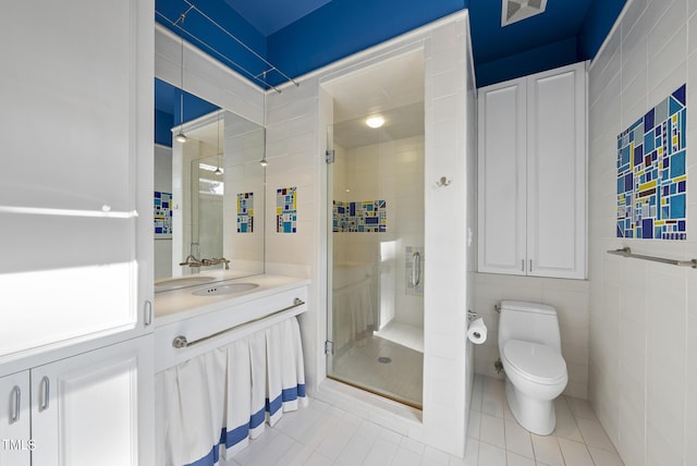 bathroom with toilet, tile walls, a shower stall, tile patterned flooring, and vanity