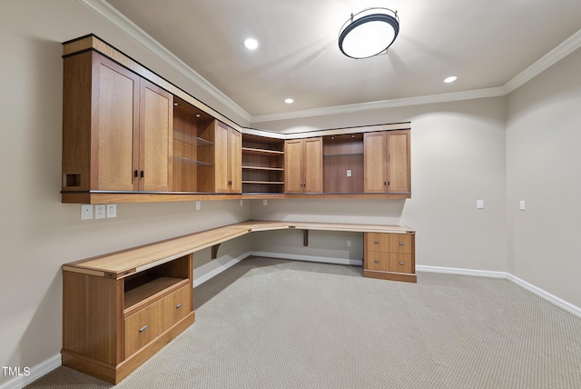 unfurnished office featuring baseboards, recessed lighting, ornamental molding, built in desk, and light colored carpet