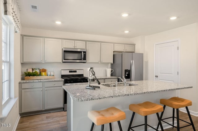 kitchen with appliances with stainless steel finishes, a center island with sink, sink, and a breakfast bar