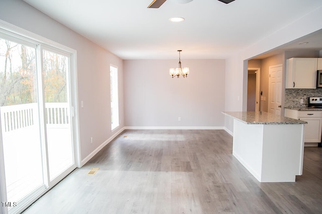 kitchen with ceiling fan with notable chandelier, a healthy amount of sunlight, hardwood / wood-style floors, and white cabinets