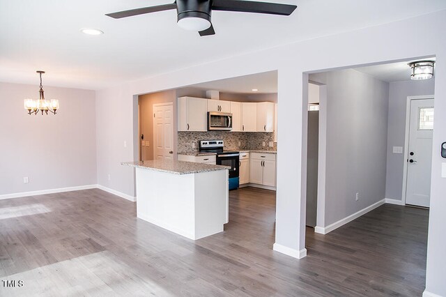 kitchen featuring hardwood / wood-style floors, ceiling fan with notable chandelier, light stone counters, stainless steel appliances, and white cabinetry