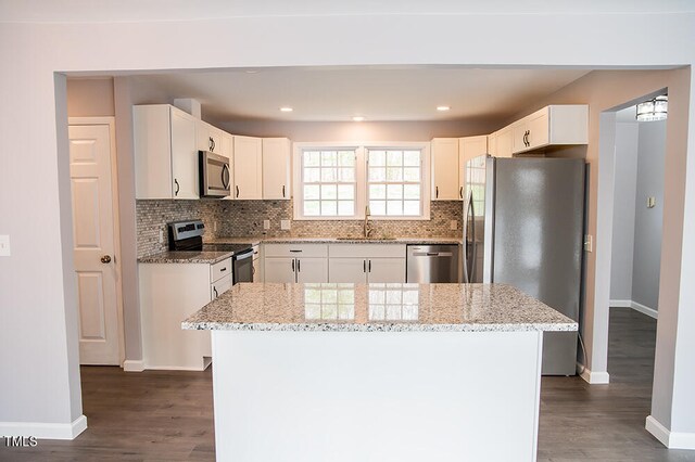 kitchen featuring a center island, dark hardwood / wood-style flooring, stainless steel appliances, and light stone countertops