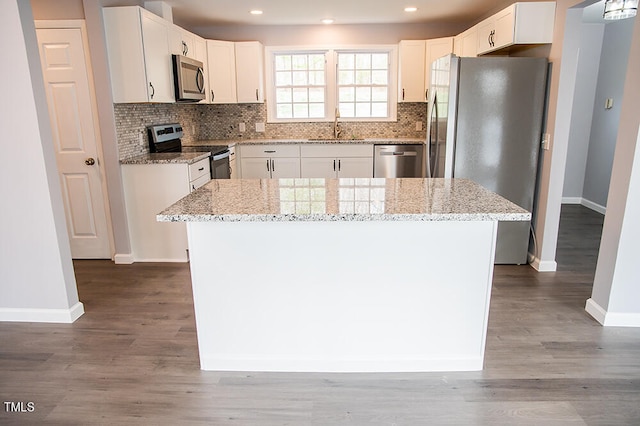 kitchen with a kitchen island, hardwood / wood-style floors, and appliances with stainless steel finishes