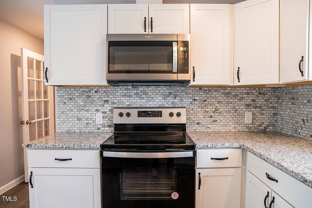 kitchen with white cabinets, backsplash, light stone counters, and stainless steel appliances