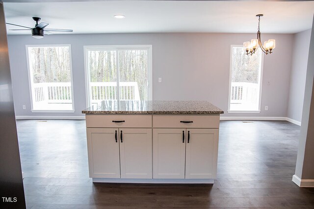 kitchen featuring white cabinetry, light stone counters, ceiling fan with notable chandelier, and dark hardwood / wood-style flooring