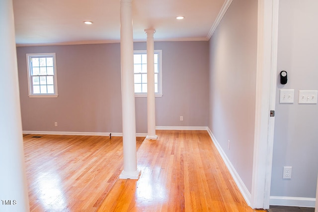 spare room featuring a wealth of natural light, crown molding, ornate columns, and light hardwood / wood-style floors