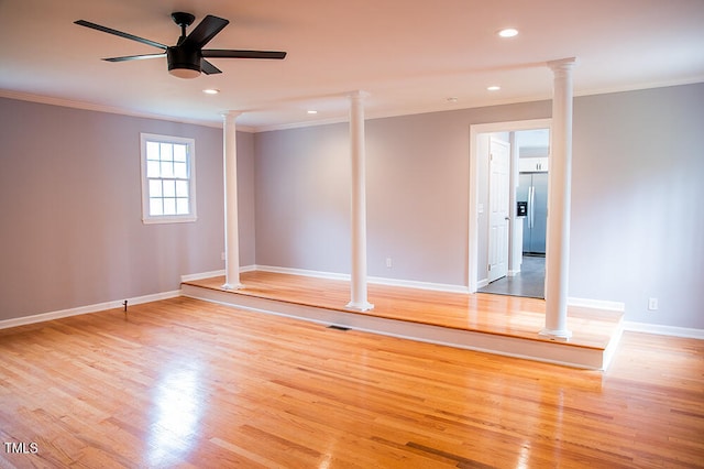 unfurnished room featuring crown molding, ceiling fan, light wood-type flooring, and decorative columns