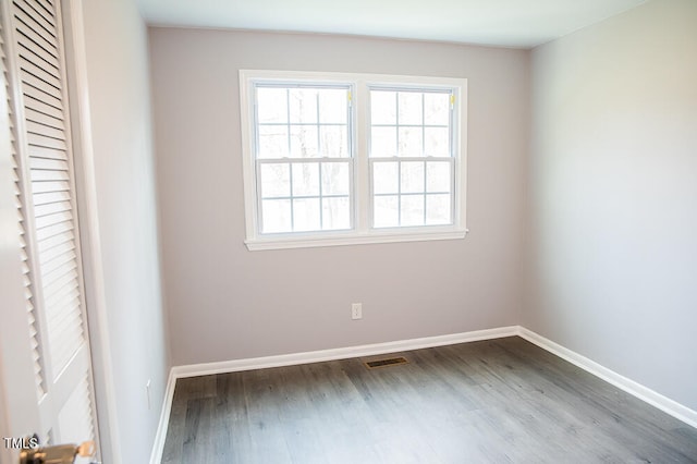 empty room featuring a healthy amount of sunlight and dark hardwood / wood-style floors