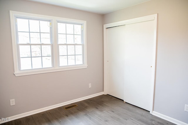 unfurnished bedroom featuring a closet, wood-type flooring, and multiple windows