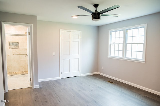 unfurnished bedroom with connected bathroom, hardwood / wood-style flooring, a closet, and ceiling fan