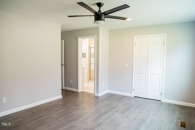 unfurnished bedroom with light hardwood / wood-style flooring, ensuite bathroom, ceiling fan, and a closet