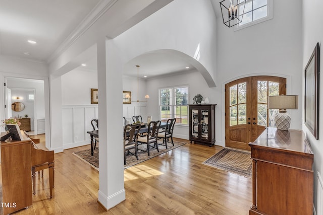 entrance foyer with ornamental molding, french doors, a notable chandelier, and light wood-type flooring