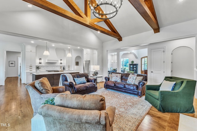 living room featuring light wood-type flooring, beamed ceiling, a chandelier, and high vaulted ceiling