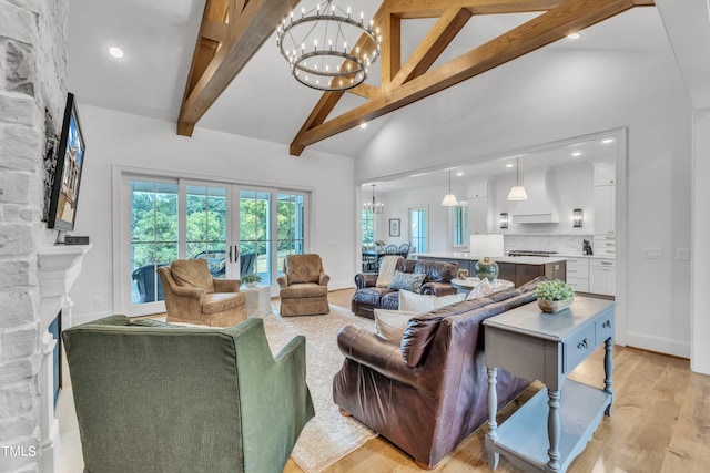 living room featuring a fireplace, light wood-type flooring, a notable chandelier, beam ceiling, and high vaulted ceiling