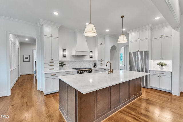 kitchen featuring white cabinetry, custom exhaust hood, a kitchen island with sink, and stainless steel appliances