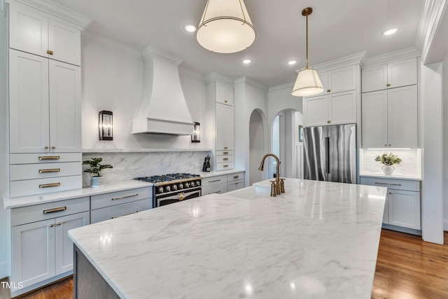 kitchen with stainless steel appliances, pendant lighting, light stone countertops, sink, and custom exhaust hood