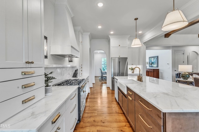 kitchen with white cabinets, sink, custom exhaust hood, pendant lighting, and appliances with stainless steel finishes