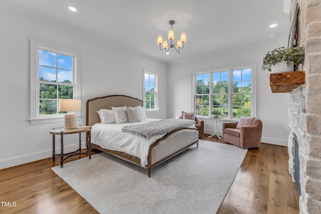 bedroom featuring ornamental molding, wood-type flooring, and an inviting chandelier