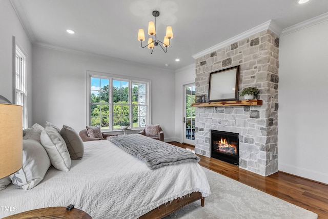 bedroom featuring hardwood / wood-style floors, a fireplace, crown molding, and an inviting chandelier