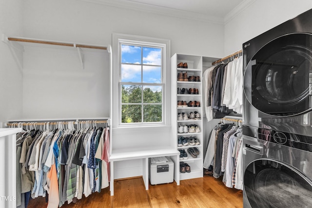 spacious closet featuring hardwood / wood-style flooring and stacked washer / drying machine