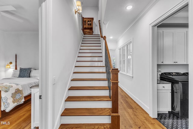 staircase featuring washing machine and dryer, wood-type flooring, and crown molding